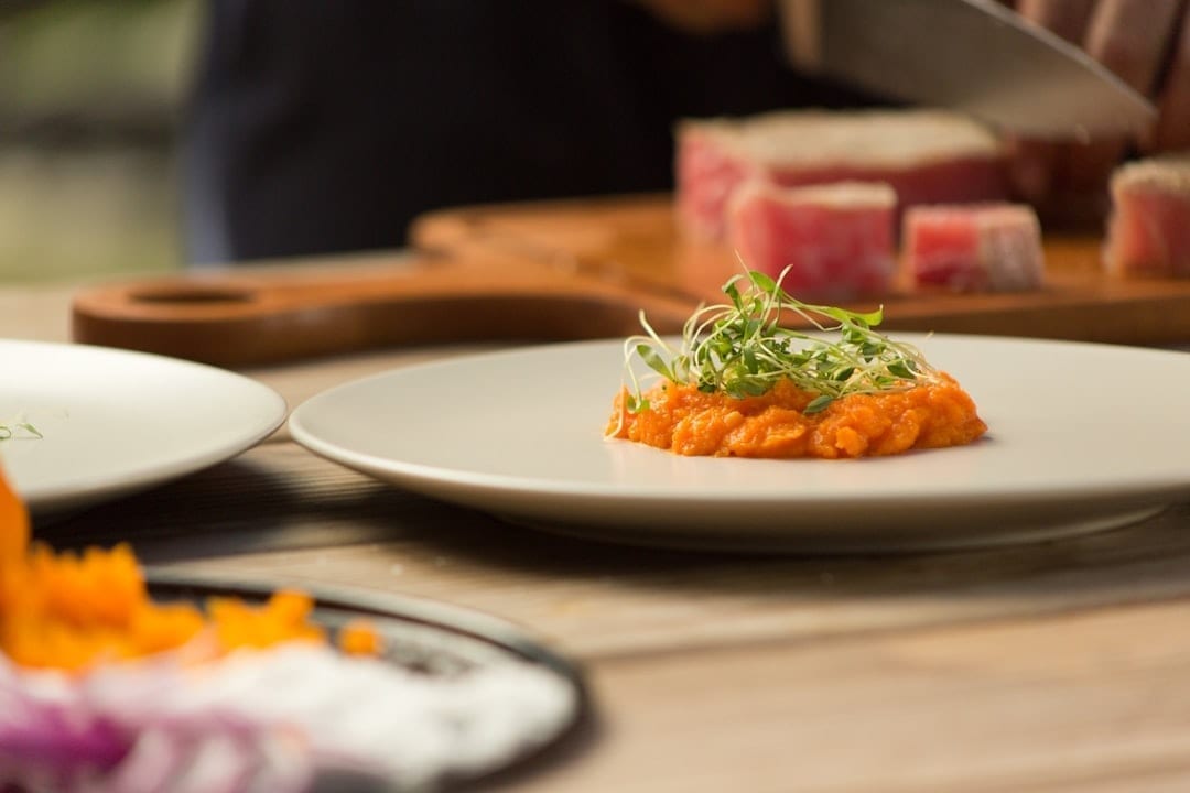 Restaurant owner scheduling food posts on laptop during prep time